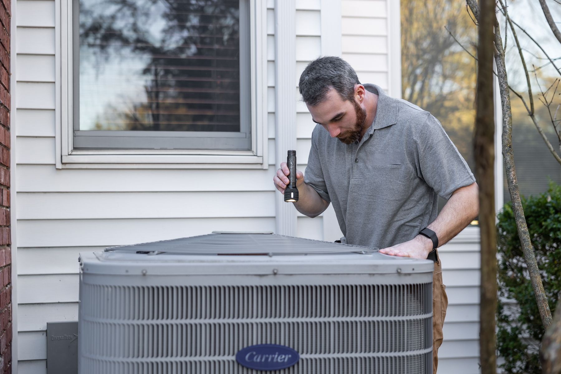 HVAC technician inspecting an outdoor air conditioning unit